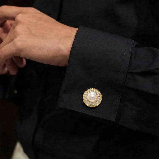 Close-up of a person adjusting their black shirt cuff, elegantly secured with a classic round pearl and rhinestone button cover. An ideal, easy-to-use cuff accessory for modern daily office wear.