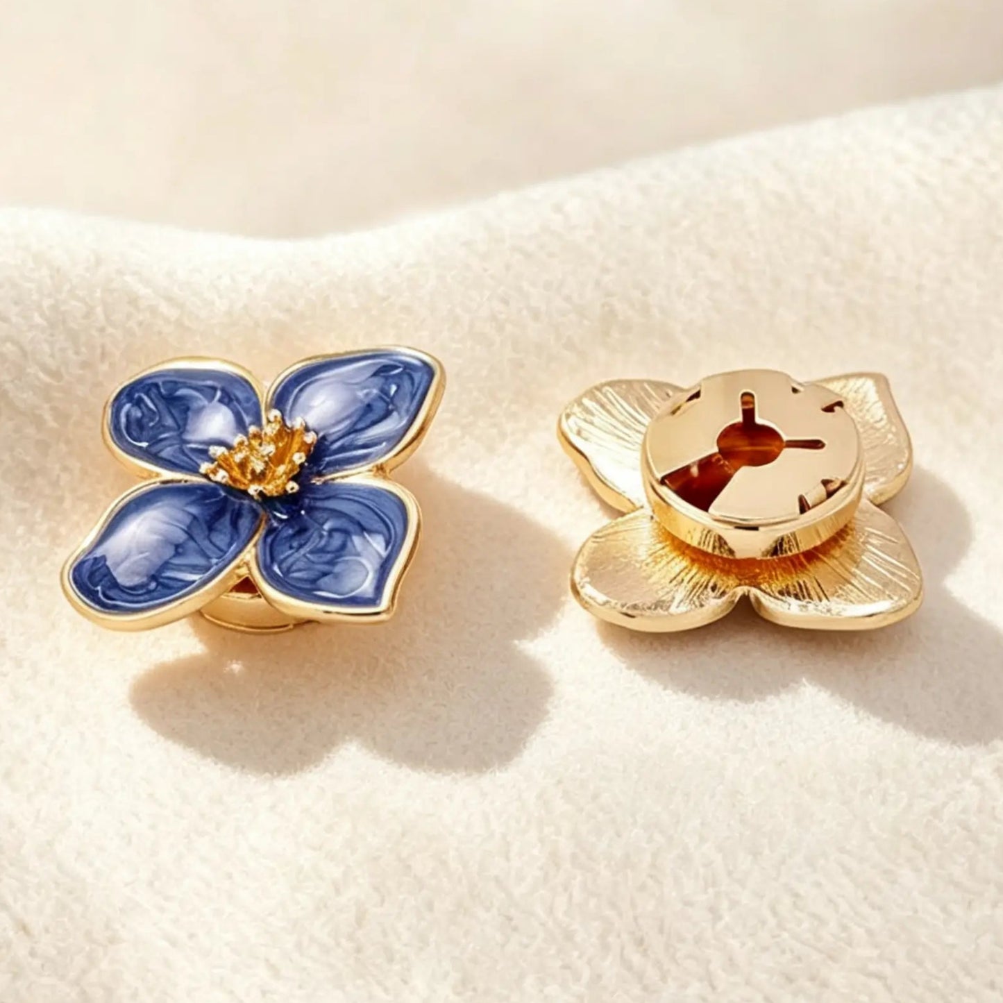 Detailed back view of a deep blue marbled enamel floral button cover. The right piece highlights the securely closed gold clip mechanism, ensuring the faux cufflink lays perfectly flat and provides a seamless, zero-bulk fit on shirt cuffs.