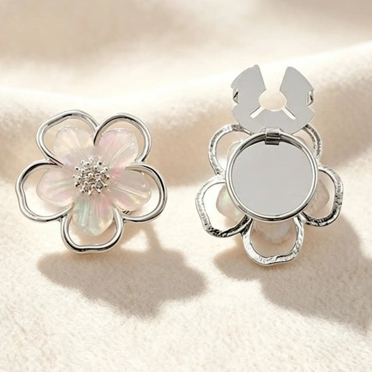 An ethereal silver five-petal floral button cover featuring translucent pearlescent inlay and a sparkling crystal center. Set against a soft cream background, the open clasp demonstrates the effortless, no-sew transformation into a chic faux cufflink.