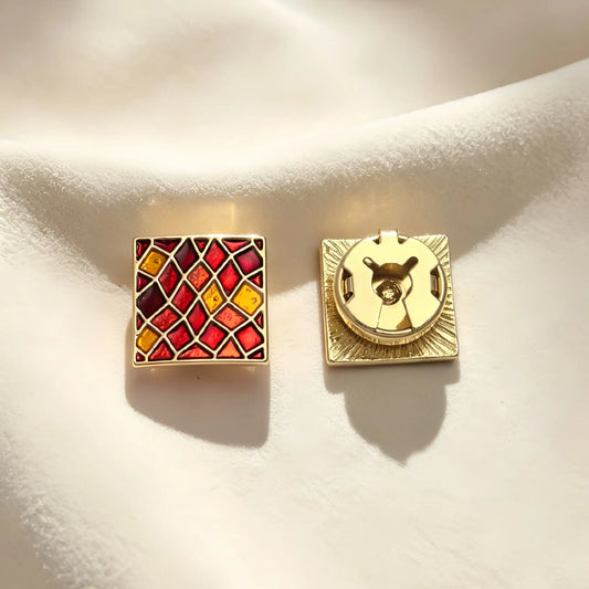A pair of light luxury square button covers featuring a warm red and amber stained glass mosaic pattern with gold edges. The right piece highlights the secure closed gold backing, perfect for an elegant Art Deco cuff upgrade.