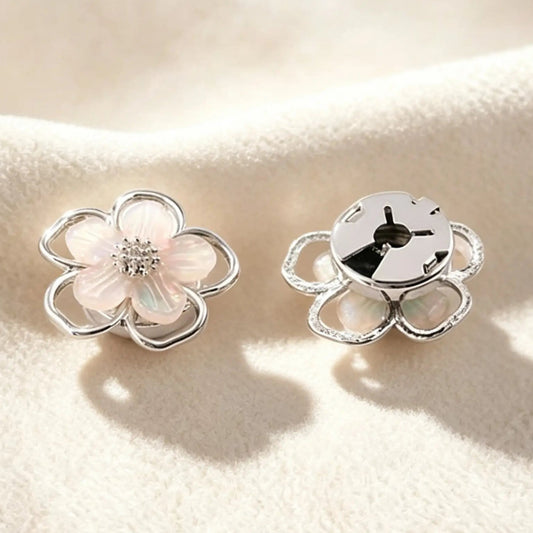 Close-up of a delicate silver pearlescent flower cuff accessory. Highlighting the securely closed back, this realistically proportioned piece promises a subtle, light luxury upgrade without damaging delicate blouse fabrics.