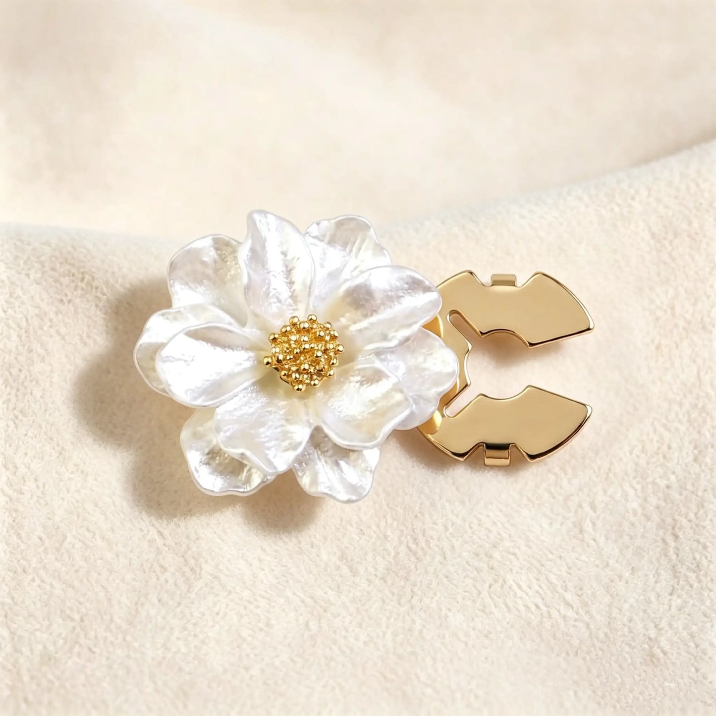 Close-up of a pearlescent white floral button cover with a crushed shell texture and gold core. The right side shows the open gold attachment clip, demonstrating a no-sew cuff upgrade solution.
