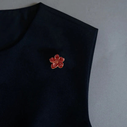 A sophisticated photo showcasing a 2-in-1 burgundy wine red enamel floral accessory utilized as a delicate brooch pin on a black sleeveless top. This deep, rich color and classic design offer an effortless touch of vintage quiet luxury to any capsule wardrobe.