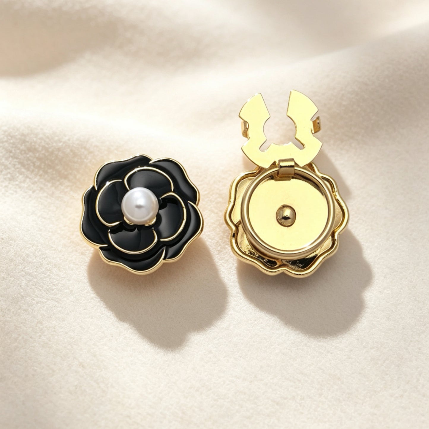 Elegant black enamel camellia floral button cover featuring a classic white pearl center and gold edges. The right piece shows the open gold clasp mechanism, perfect for a designer-inspired, no-sew French cuff upgrade.
