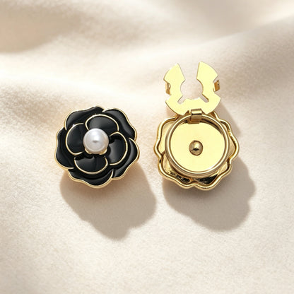 Elegant black enamel camellia floral button cover featuring a classic white pearl center and gold edges. The right piece shows the open gold clasp mechanism, perfect for a designer-inspired, no-sew French cuff upgrade.