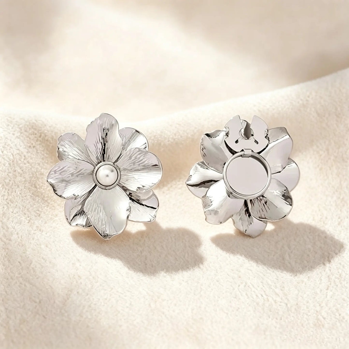 Minimalist brushed silver floral button cover with a pearl core. Displayed with the attachment clip fully open against a soft cream white background, perfect for a subtle, everyday quiet luxury cuff transformation.