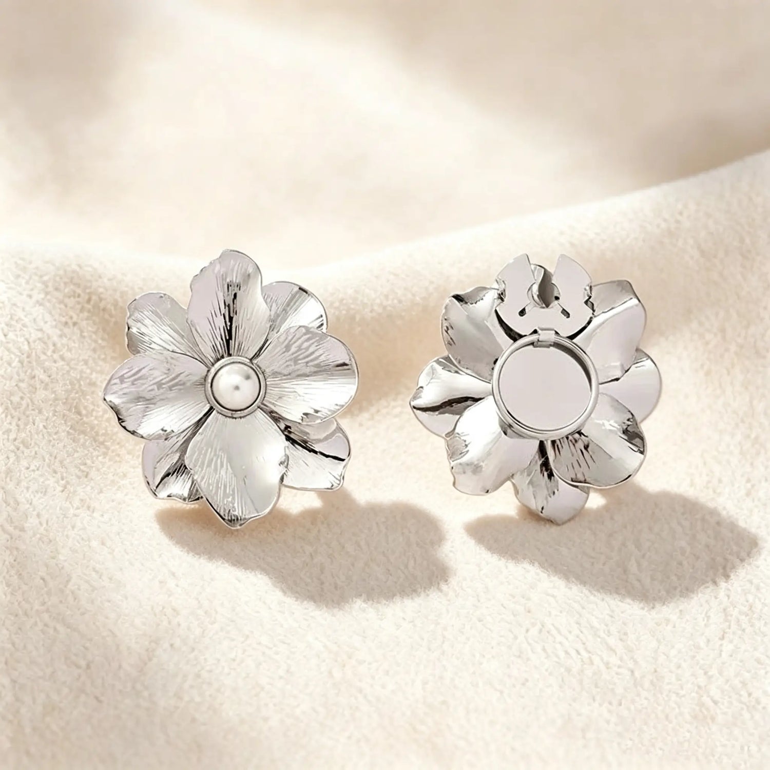 Minimalist brushed silver floral button cover with a pearl core. Displayed with the attachment clip fully open against a soft cream white background, perfect for a subtle, everyday quiet luxury cuff transformation.