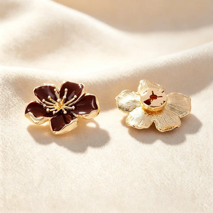 Luxurious burgundy wine enamel floral button cover distinguished by its detailed metallic gold stamen. Accompanied by the open gold back clip, it offers a sophisticated pop of color and a quiet luxury transformation for everyday blouses.