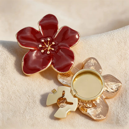 Close-up of a luxurious burgundy red enamel floral button cover featuring glossy petals and gold edges. The lower piece displays the gold open hinge mechanism, demonstrating how to easily attach this vintage-style faux cufflink to any shirt.