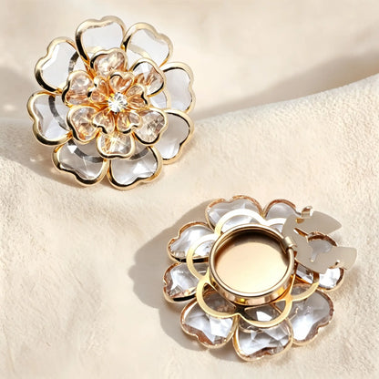 Luminous champagne clear crystal floral button cover accented with gold outlines. The right side reveals the gold open clip back designed to easily snap over standard shirt buttons for a light luxury look.