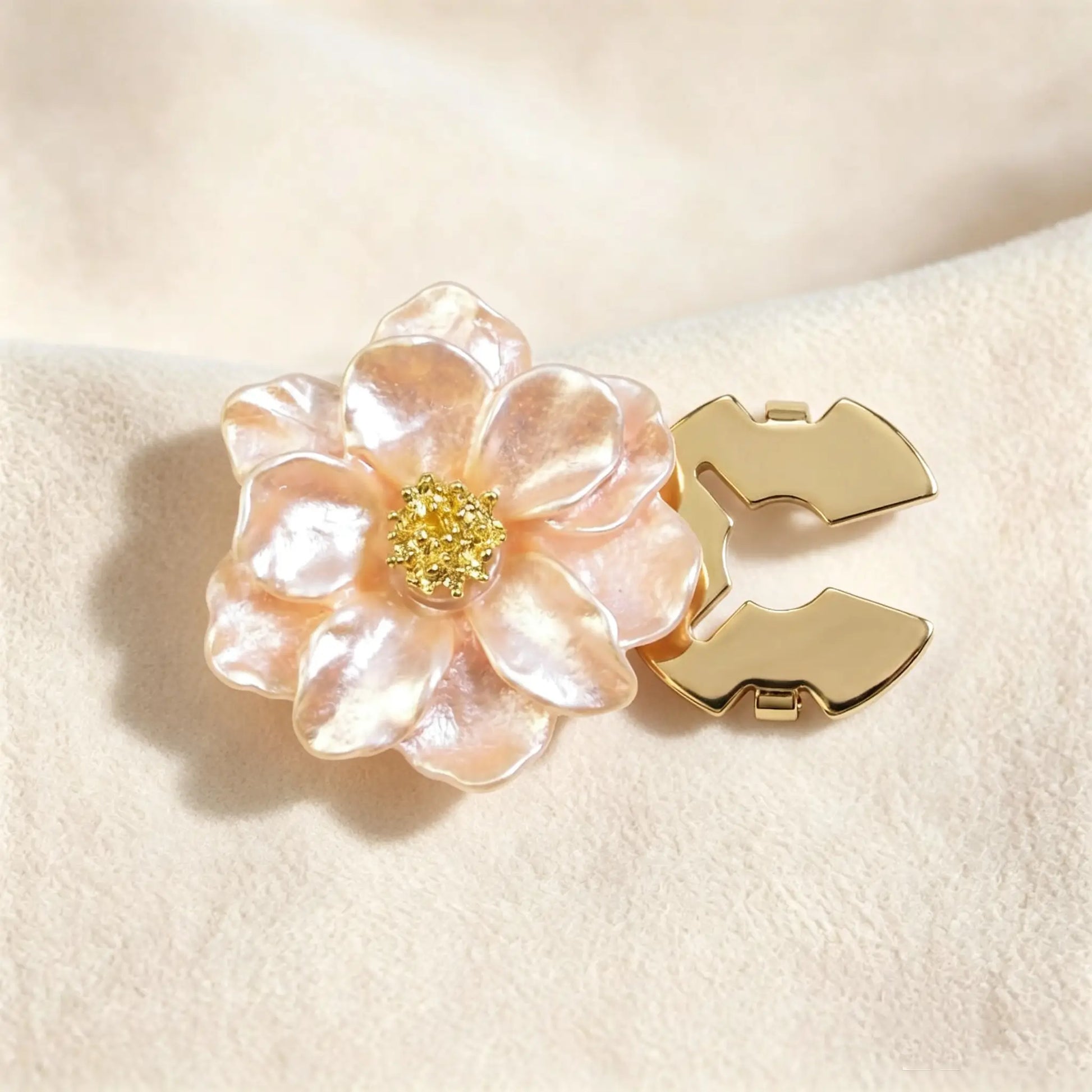 Soft champagne peach pearlescent floral button cover displaying a radiant finish. Accompanied by a clear view of the open gold hinge mechanism, designed to easily snap over standard shirt buttons.