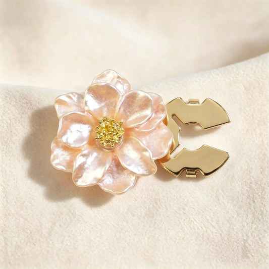 Soft champagne peach pearlescent floral button cover displaying a radiant finish. Accompanied by a clear view of the open gold hinge mechanism, designed to easily snap over standard shirt buttons.