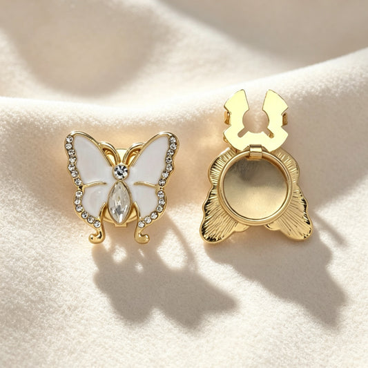 Light luxury white enamel butterfly button cover accented with a brilliant marquise crystal. Accompanied by a clear view of the open gold attachment clip, offering an effortless and whimsical cuff upgrade.