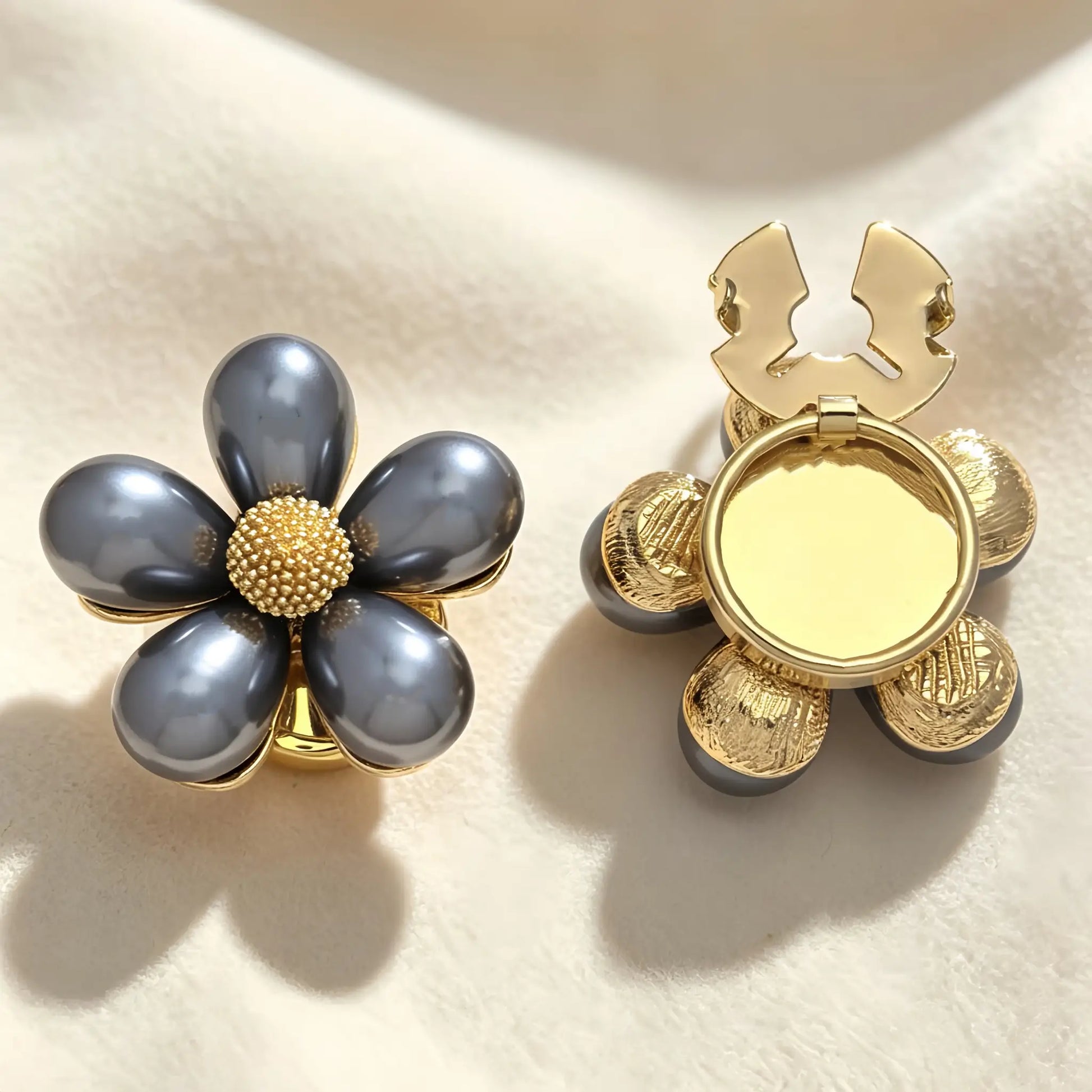 Elegant dark grey pearl floral button cover with a textured gold center. The right side shows the open gold hinge mechanism, designed to be easily attached as a light luxury cuff accessory.