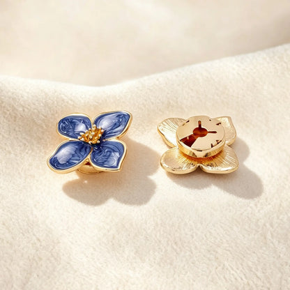 Detailed back view of a deep blue marbled enamel floral button cover. The right piece highlights the securely closed gold clip mechanism, ensuring the faux cufflink lays perfectly flat and provides a seamless, zero-bulk fit on shirt cuffs.