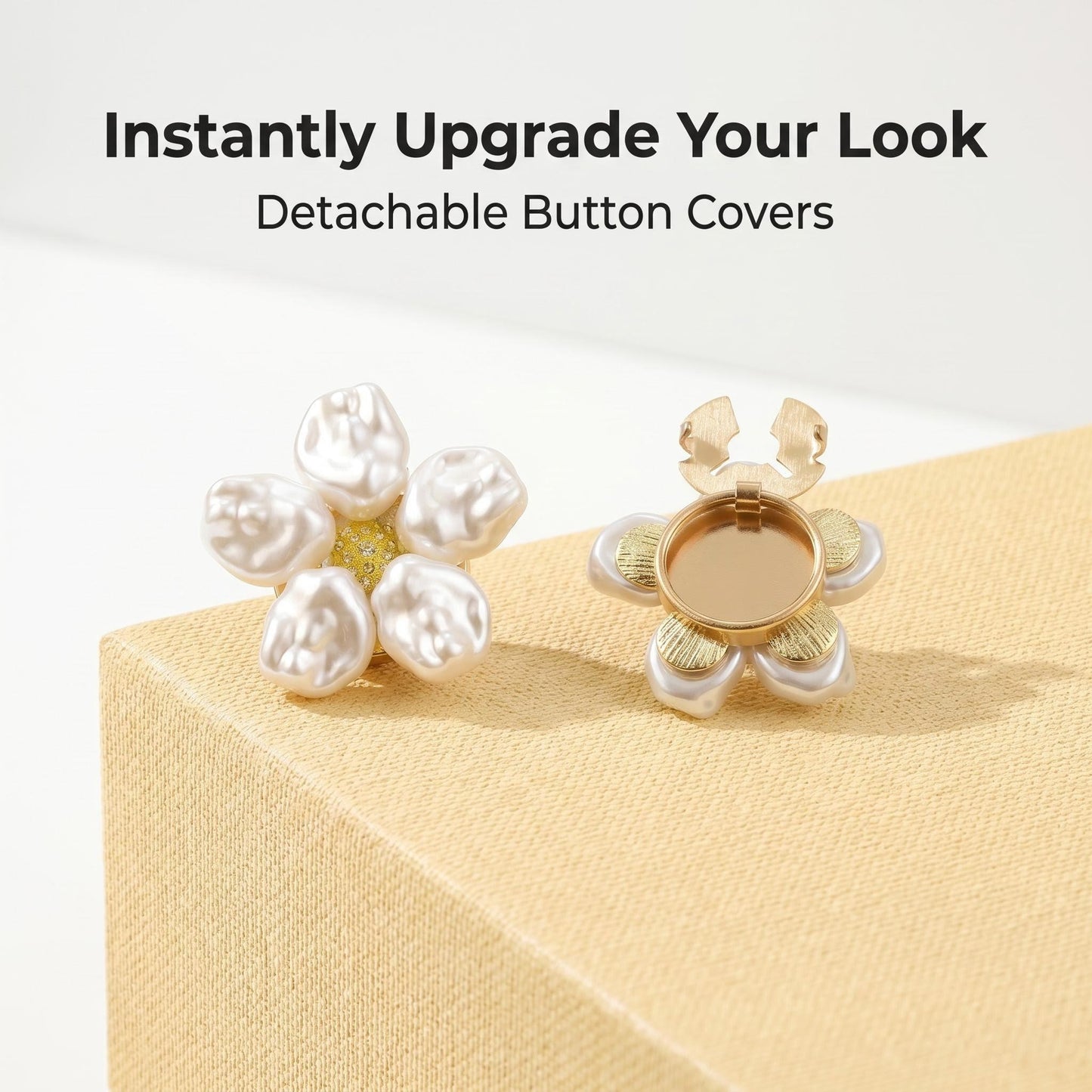 Promotional display of two detachable baroque pearl floral button covers resting on a minimalist cream textured block. The left cover displays the elegant pearl front, while the right shows the open gold clip mechanism. Overlay text reads "Instantly Upgrade Your Look - Detachable Button Covers".