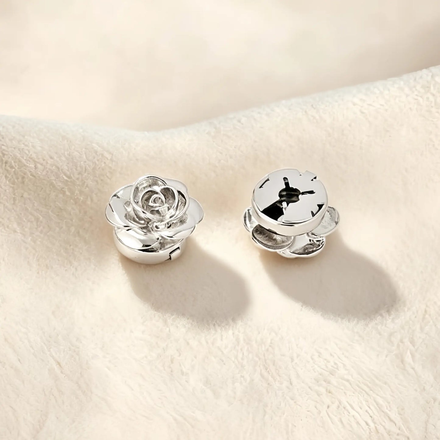 Detailed view of a polished silver rose button cover highlighting its closed back mechanism. This secure design allows the floral accessory to sit flush against the fabric, offering a refined touch of everyday elegance.