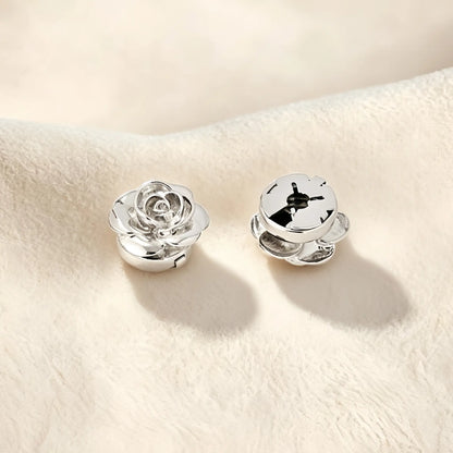 Detailed view of a polished silver rose button cover highlighting its closed back mechanism. This secure design allows the floral accessory to sit flush against the fabric, offering a refined touch of everyday elegance.