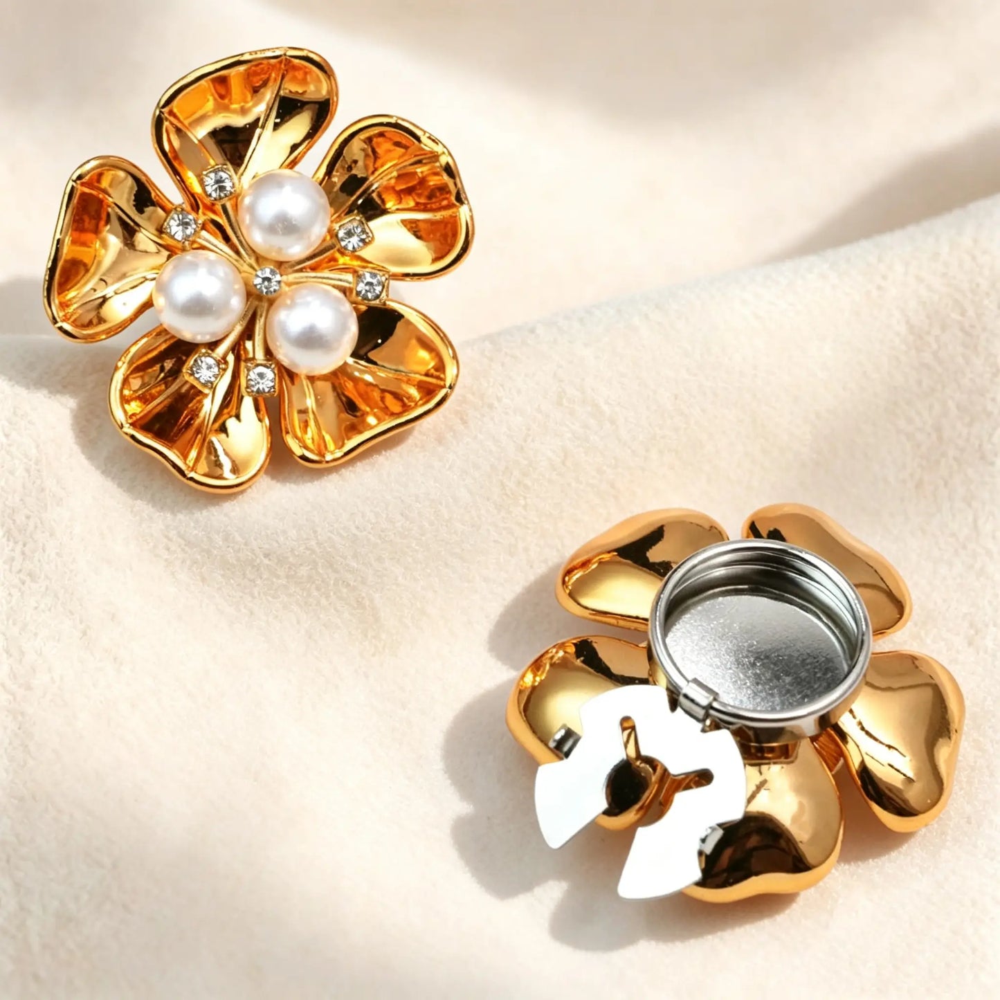 High-shine glossy gold floral button cover centered with three white pearls and sparkling rhinestones. Includes a detailed view of the gold open clasp back, designed to securely fit over standard shirt cuffs.