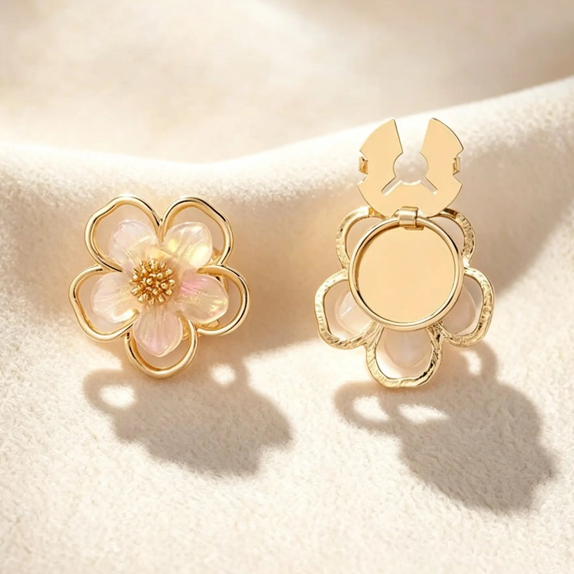 A luxurious gold five-petal floral button cover detailed with pearlescent petals and a crystal cluster center. Displayed on cream fabric with the gold attachment clip fully open, perfect for adding a touch of vintage femininity to everyday workwear.