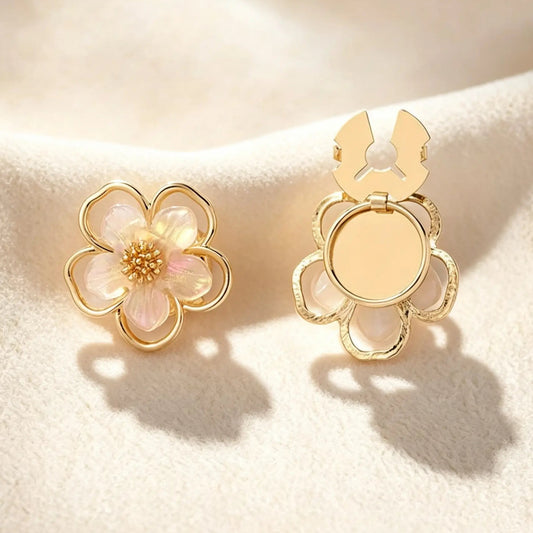 A luxurious gold five-petal floral button cover detailed with pearlescent petals and a crystal cluster center. Displayed on cream fabric with the gold attachment clip fully open, perfect for adding a touch of vintage femininity to everyday workwear.