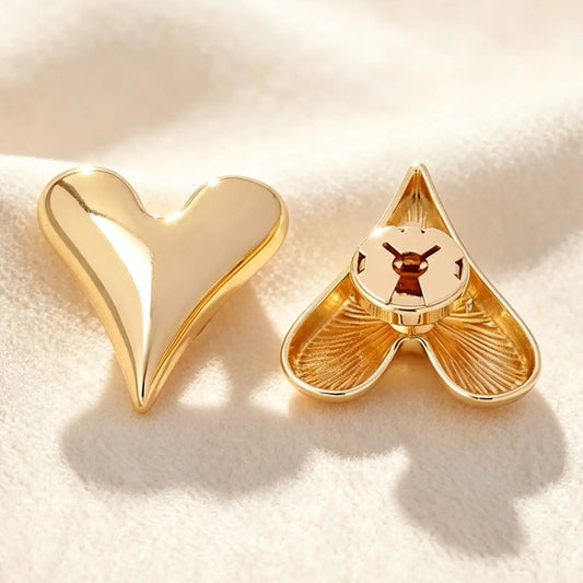 Close-up of a smooth gold heart faux cufflink on a textured cream background. The image highlights the secure closed back, ensuring a seamless, zero-bulk fit against the cuff for everyday office wear.