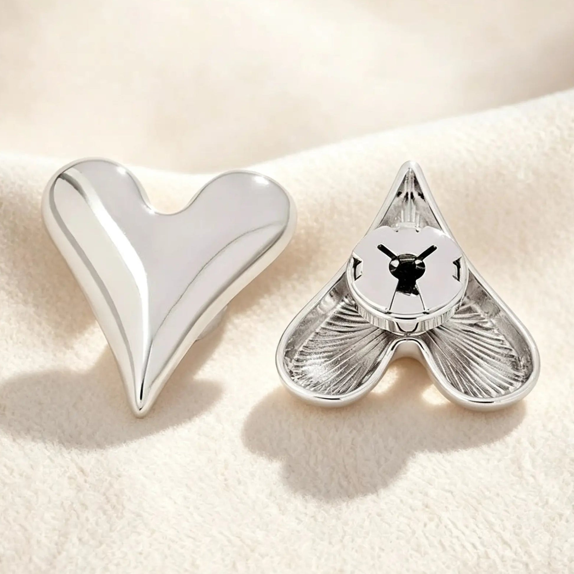 Detailed back view of a polished silver heart button cover. The firmly closed mechanism guarantees a secure grip on the button, providing a sleek jewelry finish for modern wardrobes without damaging fabrics.