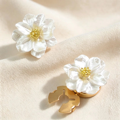 A pair of pearl white shimmering floral button covers resting on soft velvet. The image highlights both the intricate gold flower center and the secure closed gold back mechanism for effortless shirt styling.