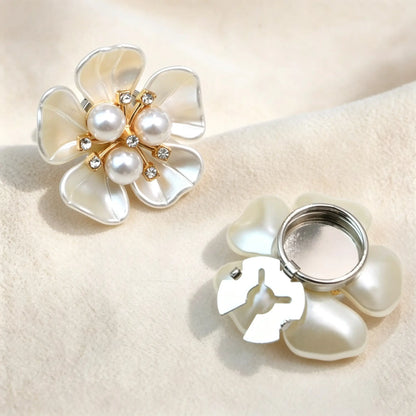 Elegant pearlescent cream white floral button cover adorned with three white pearls. Displayed with its silver detachable hinge mechanism fully open, offering a refined and versatile shirt upgrade.