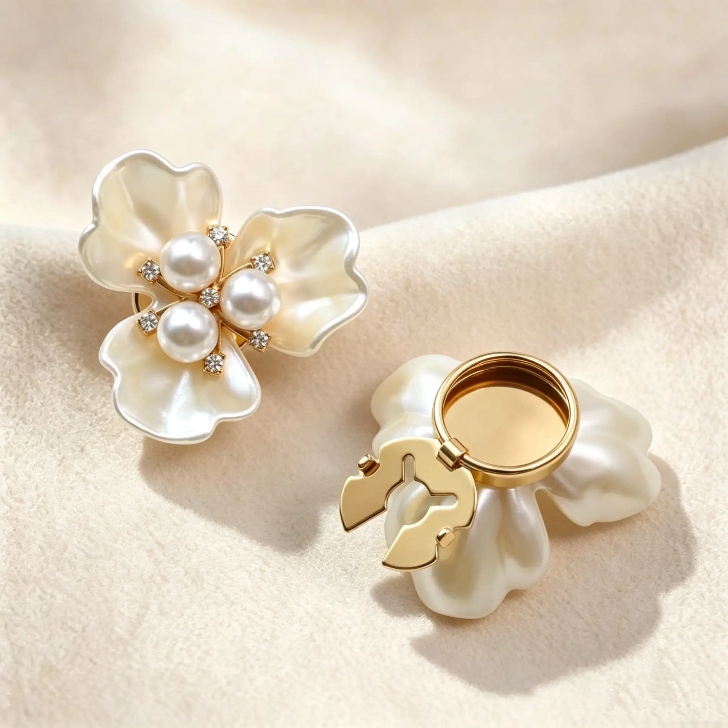 Elegant pearlescent white three-petal floral button cover featuring a center of three pearls and rhinestones. The right side shows the open gold clasp mechanism, perfect as a light luxury faux cufflink on soft textured fabric.