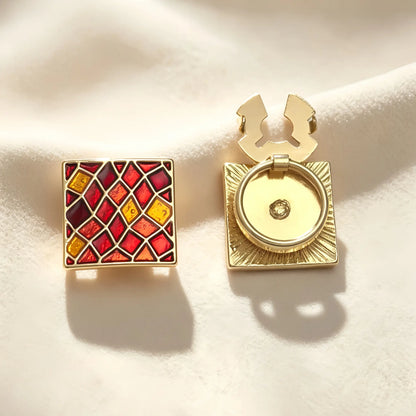 Detailed view of a vintage-style square button cover showcasing a geometric red enamel lattice design. The image emphasizes the open gold hinge mechanism, demonstrating how easily it attaches to standard shirts as a no-sew cuff accessory.