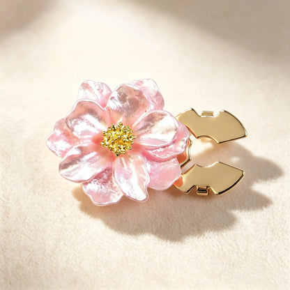 Detailed view of a rose pink shimmering floral button cover with a golden textured center. The gold open clip mechanism is displayed, illustrating how to easily transform ordinary shirt buttons into luxurious cuffs.