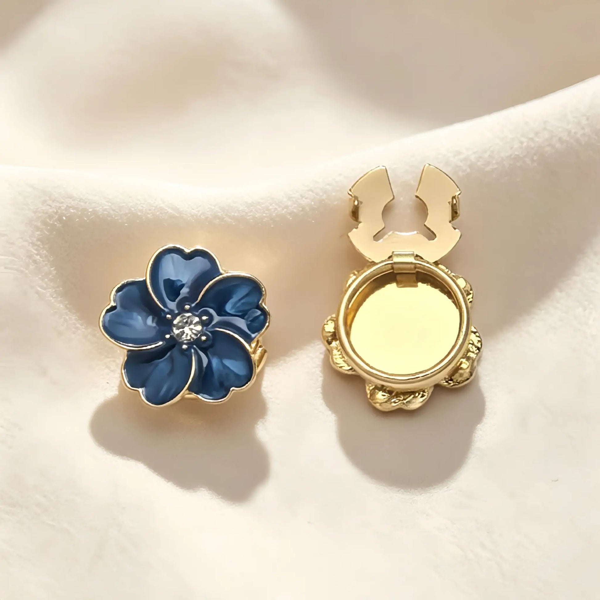 Striking sapphire blue enamel floral button cover featuring a glossy marbled finish and gold edges. Includes a clear view of the open gold hinge mechanism, ideal for an instant French cuff transformation