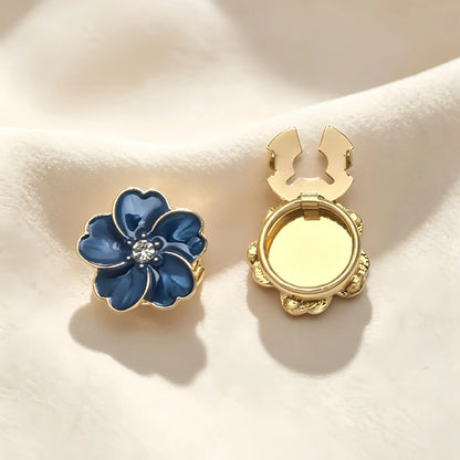 Striking sapphire blue enamel floral button cover featuring a glossy marbled finish and gold edges. Includes a clear view of the open gold hinge mechanism, ideal for an instant French cuff transformation