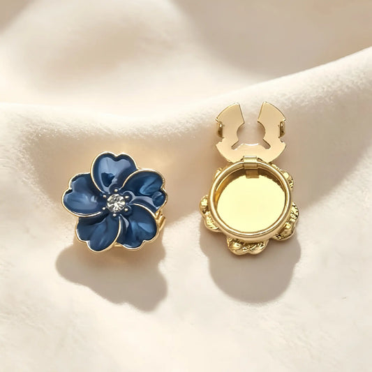 Striking sapphire blue enamel floral button cover featuring a glossy marbled finish and gold edges. Includes a clear view of the open gold hinge mechanism, ideal for an instant French cuff transformation