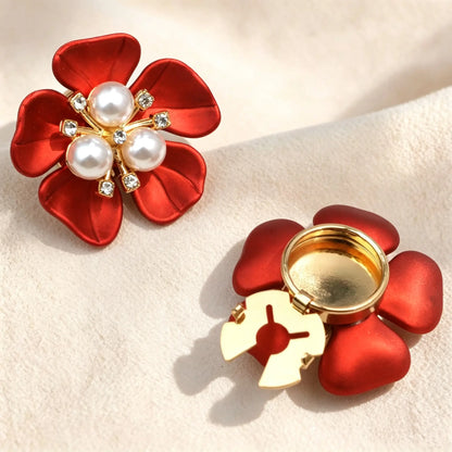 Striking satin red metallic floral button cover centered with three classic white pearls. The right piece highlights the open gold attachment clip, ideal as a luxurious cuff accessory.