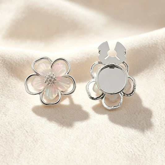 An ethereal silver five-petal floral button cover featuring translucent pearlescent inlay and a sparkling crystal center. Set against a soft cream background, the open clasp demonstrates the effortless, no-sew transformation into a chic faux cufflink.