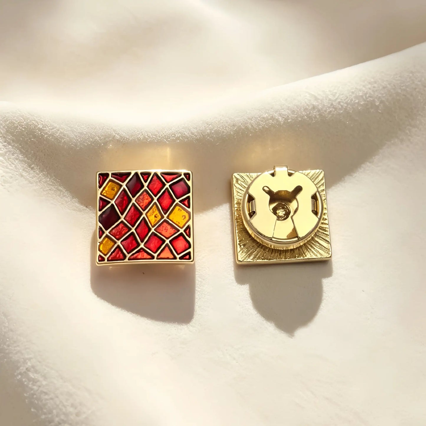 A pair of light luxury square button covers featuring a warm red and amber stained glass mosaic pattern with gold edges. The right piece highlights the secure closed gold backing, perfect for an elegant Art Deco cuff upgrade.