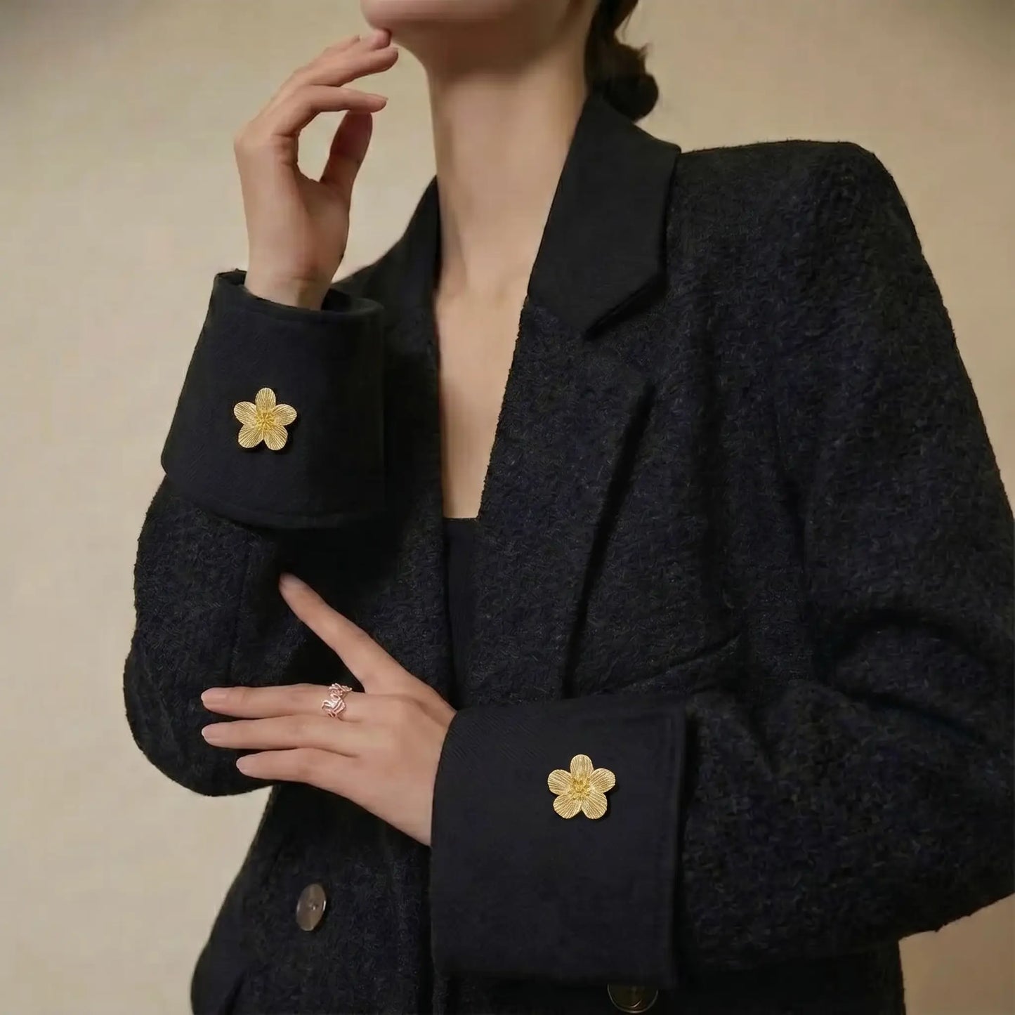 A stylish everyday outfit featuring a black textured blazer and shirt, elevated by a gold floral button cover on the cuff. Demonstrates how this jewelry piece instantly enhances daily fashion without French cuffs.