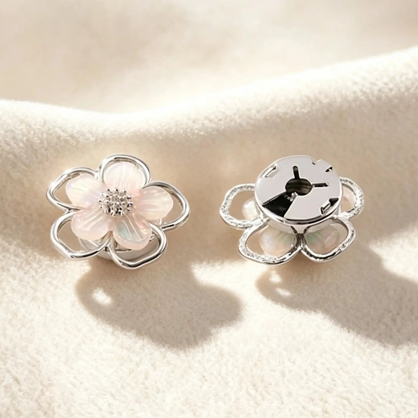 Close-up of a delicate silver pearlescent flower cuff accessory. Highlighting the securely closed back, this realistically proportioned piece promises a subtle, light luxury upgrade without damaging delicate blouse fabrics.
