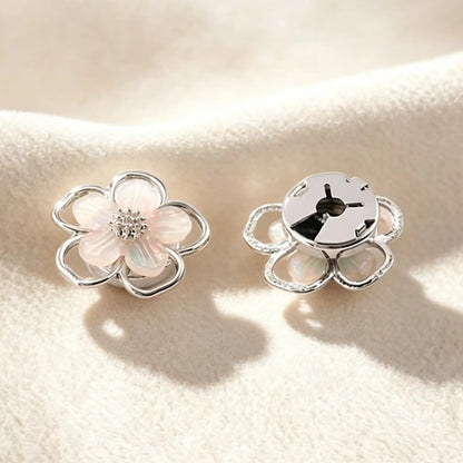 Close-up of a delicate silver pearlescent flower cuff accessory. Highlighting the securely closed back, this realistically proportioned piece promises a subtle, light luxury upgrade without damaging delicate blouse fabrics.