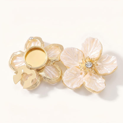 Detailed view of the no-sew snap buckle mechanism on an elegant camellia pearl button cover, showing how it securely clips onto shirt buttons.
