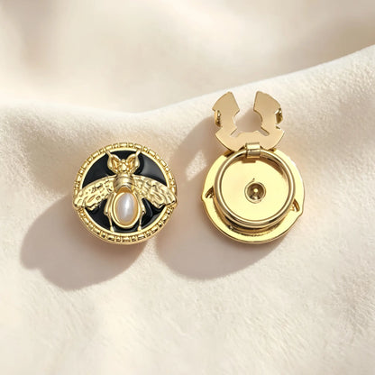 Elegant vintage-style round button cover featuring a 3D gold bee with a pearl body on a black enamel background, framed by a textured coin edge. The right piece shows the open gold hinge mechanism, perfect for a no-sew French cuff upgrade.