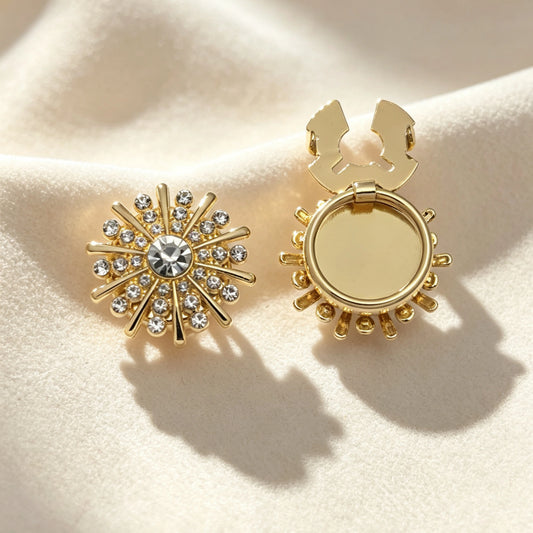 Light luxury gold sunburst button cover encrusted with sparkling rhinestones and a large center crystal. The right piece displays the open gold hinge mechanism, perfect for a no-sew French cuff upgrade on cream white fabric.