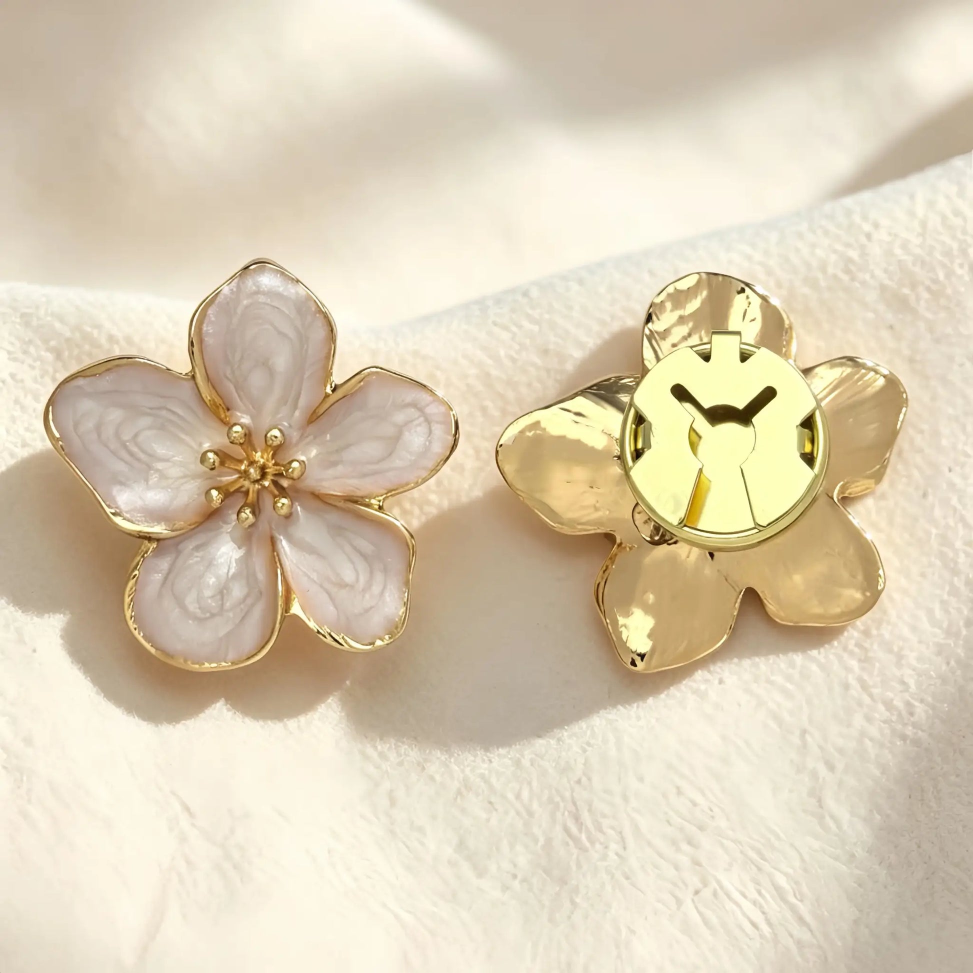 Elegant vintage-style pink enamel floral button cover with a detailed gold center, resting on soft textured fabric under warm sunlight. The right piece highlights the secure closed gold backing, perfect for functioning as a faux cufflink.