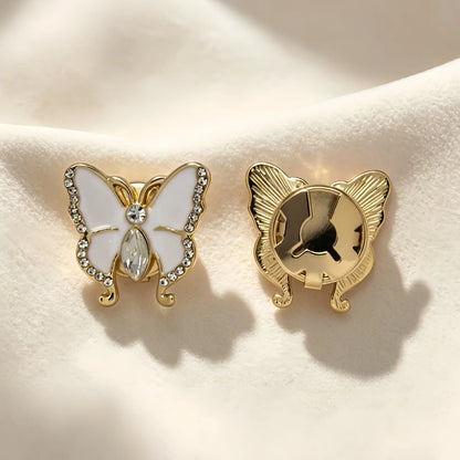 A pair of beautiful white enamel butterfly button covers with a crystal body and rhinestone edges. The right piece shows the secure closed gold clip, serving beautifully as an elegant shirt cuff transformation.