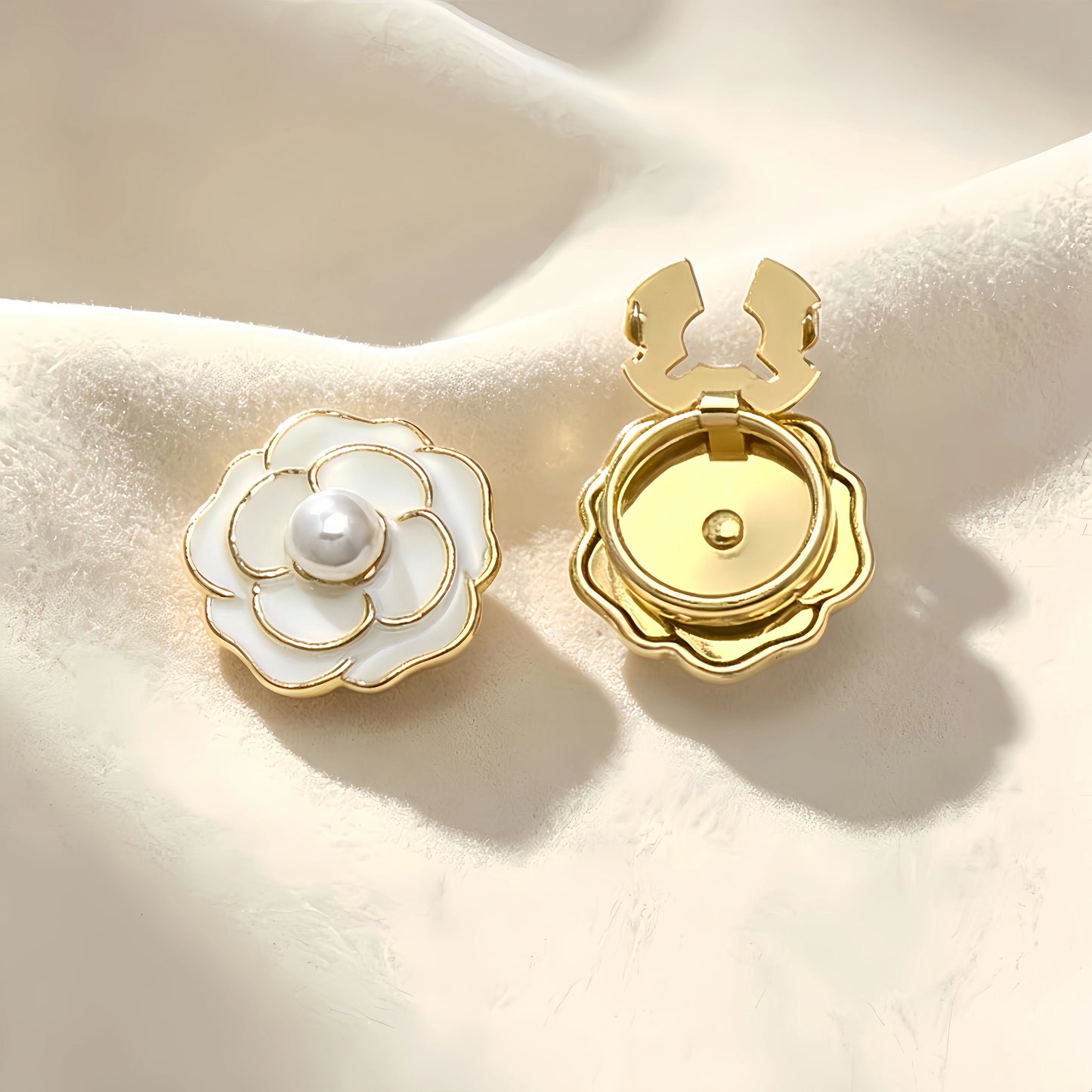 Classic white enamel camellia floral button cover featuring a central pearl and delicate gold outlines. Accompanied by a clear view of the open gold hinge mechanism, offering an effortless light luxury cuff transformation.