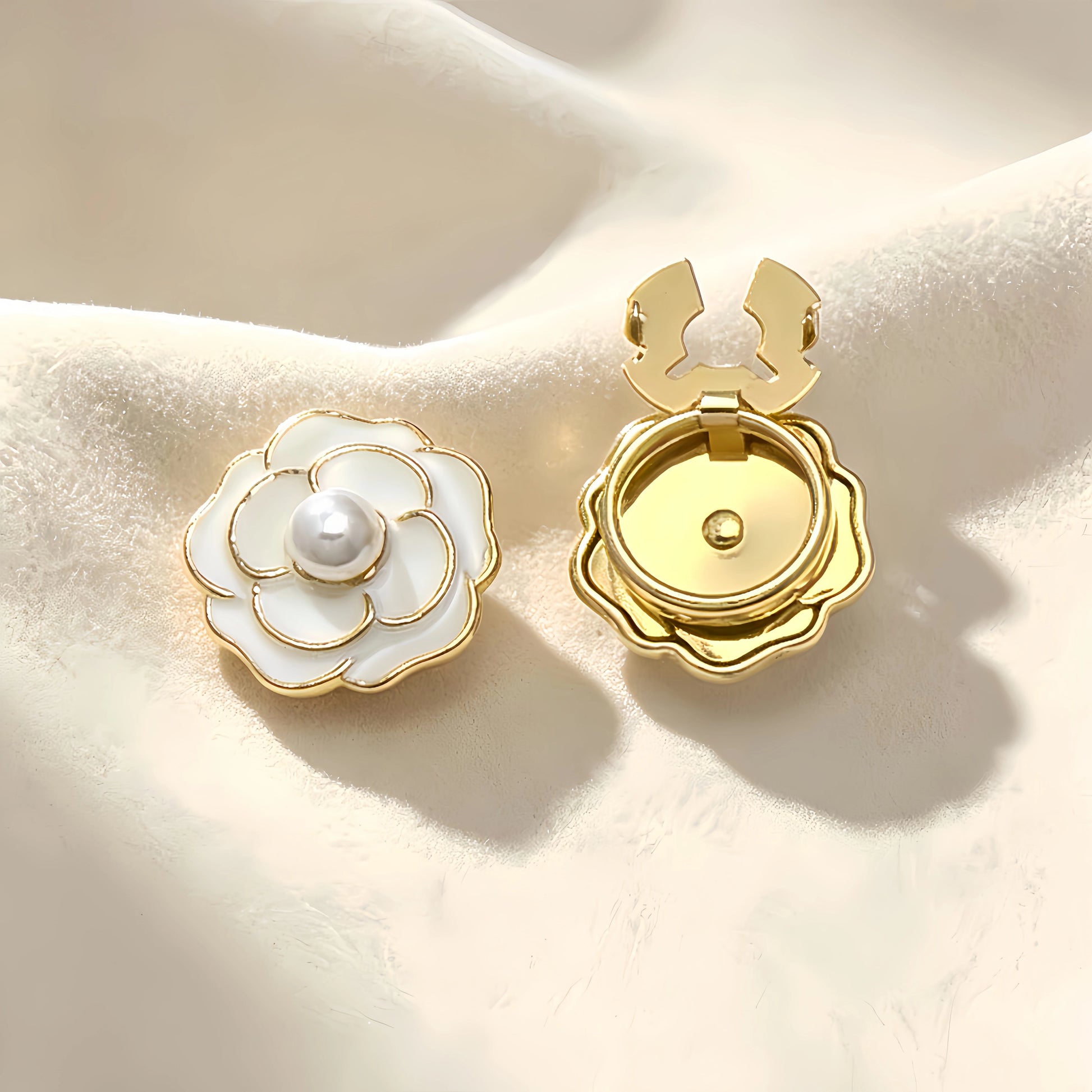 Classic white enamel camellia floral button cover featuring a central pearl and delicate gold outlines. Accompanied by a clear view of the open gold hinge mechanism, offering an effortless light luxury cuff transformation.