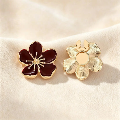 Detailed view of a deep wine red enamel floral button cover. The right piece displays the securely closed attachment mechanism and its textured gold finish, guaranteeing a refined, realistically proportioned upgrade for modern shirt cuffs.