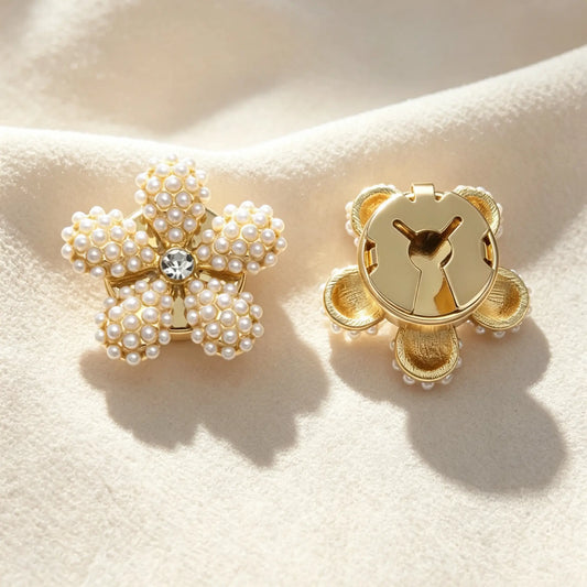 Elegant floral button cover made of clustered mini white pearls with a sparkling rhinestone core. Shows the secure closed gold backing, resting on soft fabric under warm sunlight, ideal for vintage French-style cuff styling.